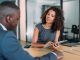 Shot of two colleagues having a discussion in the board room. Confident business people working together in the office. Corporate business persons discussing new project and sharing ideas in the workplace. Social dialogue taking place