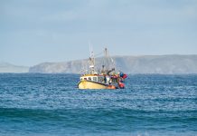 Yellow British fishing boat trawler alone in the English channel islands waters after leaving EU with no French fisherman boats or nets in view. Territorial waters under England's control.