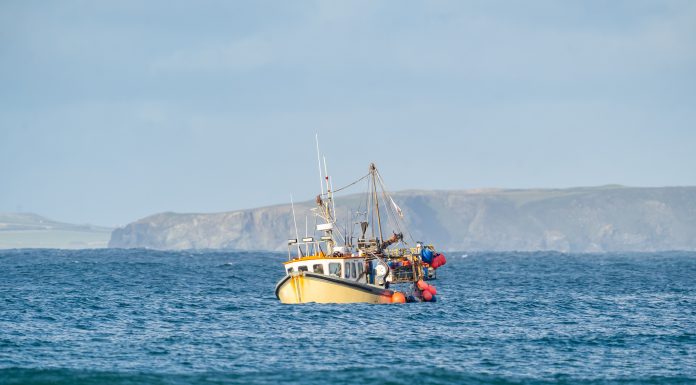 Yellow British fishing boat trawler alone in the English channel islands waters after leaving EU with no French fisherman boats or nets in view. Territorial waters under England's control.