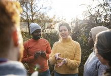 A multiracial group of volunteers wearing warm casual clothing and accessories on a sunny cold winters day. They are talking before they start working on a community farm, planting trees and performing other tasks.