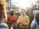 A multiracial group of volunteers wearing warm casual clothing and accessories on a sunny cold winters day. They are talking before they start working on a community farm, planting trees and performing other tasks.