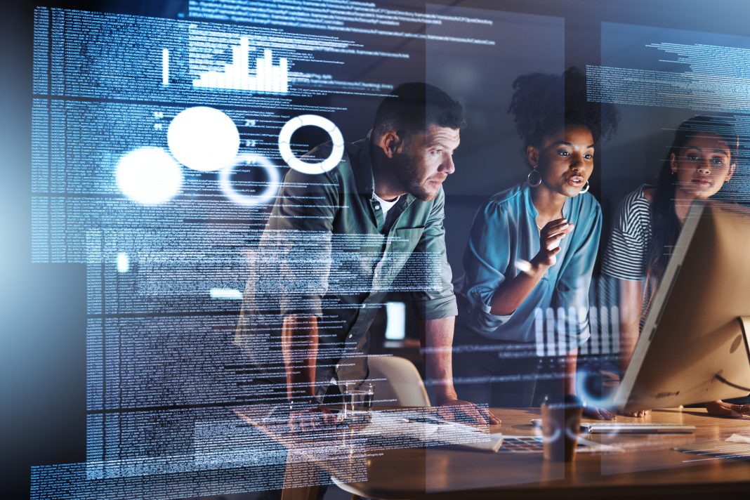 Shot of a group of programmers working together on a computer code at night