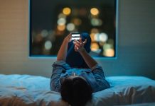 Woman lying down on bed and using smart phone at night, AI's impact on mental health