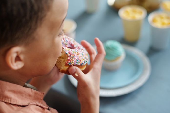 Little boy eating delicious donut
