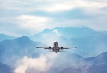jet flight travel concept stock photo. Airplane fly above amazing blue misty mountain