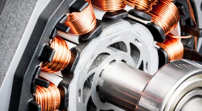 Detail of copper winding, stack and shaft of a electric permeant magnet motor for home appliances. Selective focus and white background.