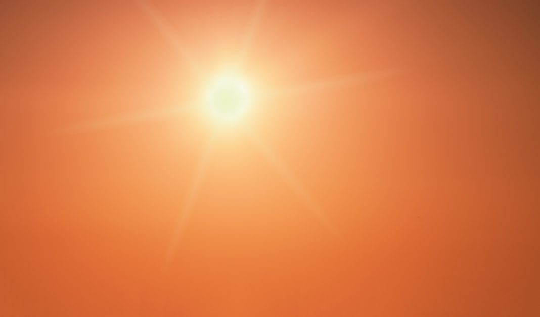 The sun shining brightly in a clear orange sky