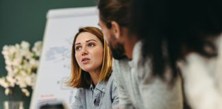 Young businesswoman having a discussion with her colleagues in a boardroom. Creative young businesswoman sharing her ideas during a meeting in a modern office.