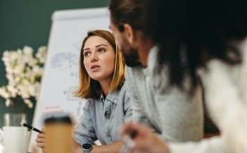 Young businesswoman having a discussion with her colleagues in a boardroom. Creative young businesswoman sharing her ideas during a meeting in a modern office.