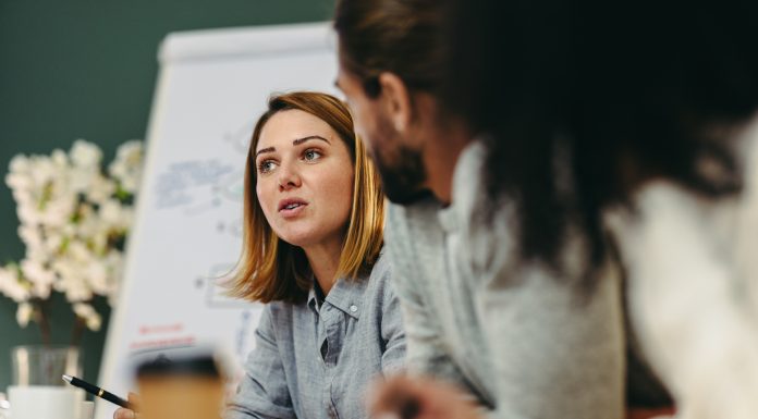 Young businesswoman having a discussion with her colleagues in a boardroom. Creative young businesswoman sharing her ideas during a meeting in a modern office.