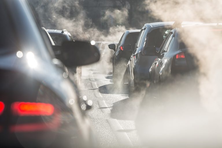 Blurred silhouettes of cars surrounded by steam from the exhaust pipes