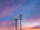 Two towers providing cellular broadband and data service to rural areas against the sunset. Illustrates digital divide.