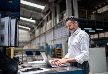 Mature businessman using laptop in a factory