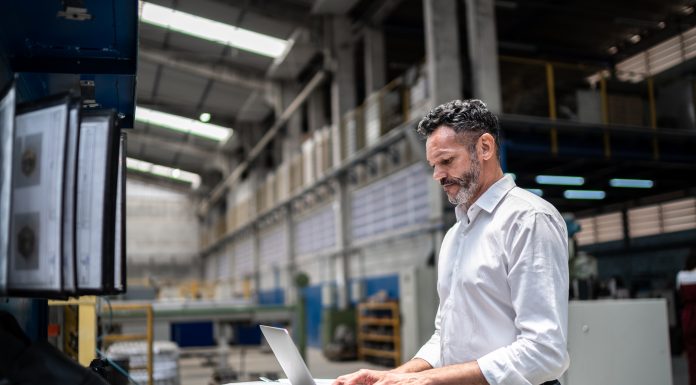 Mature businessman using laptop in a factory