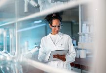 Young Female Scientist Noting Results Of Experiment In A Lab