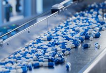 Blue Capsules on Conveyor at Modern Pharmaceutical Factory. Tablet and Capsule Manufacturing Process. Close-up Shot of Medical Drug Production Line.