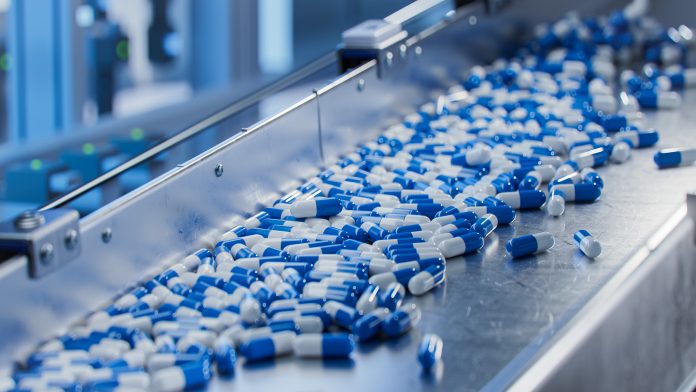 Blue Capsules on Conveyor at Modern Pharmaceutical Factory. Tablet and Capsule Manufacturing Process. Close-up Shot of Medical Drug Production Line.