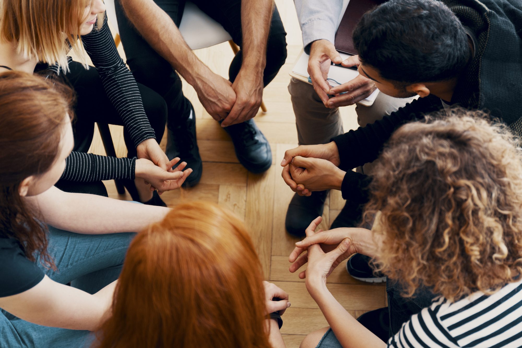 High angle of a group of teenagers sitting in a circle during group therapy for bullying victims