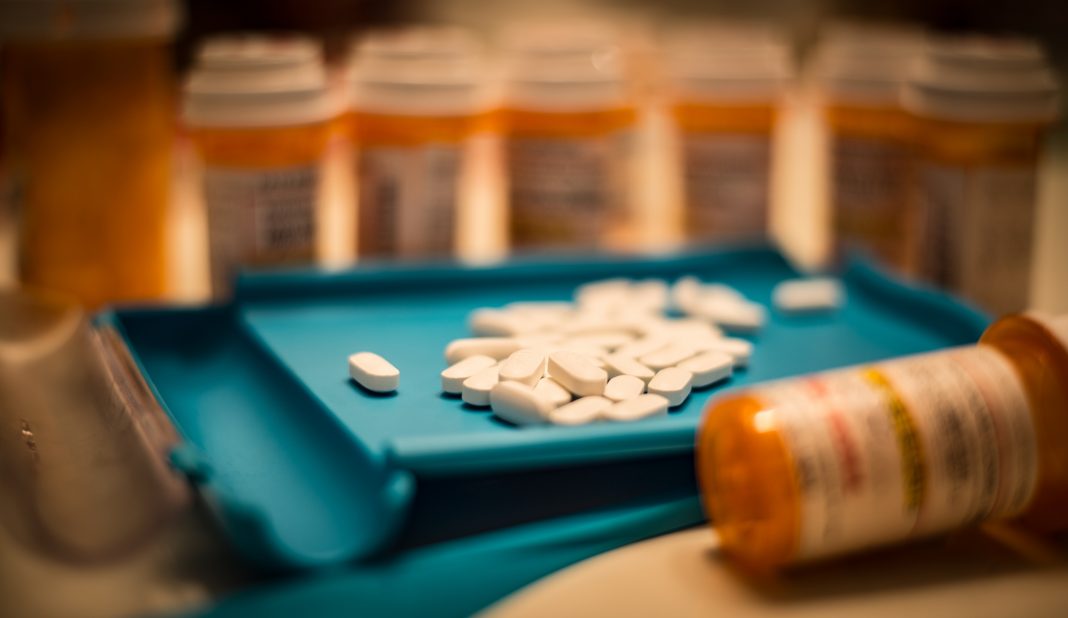 Unsorted prescription pills sit in a pharmacist's counting tray before they are bottled, opioid use