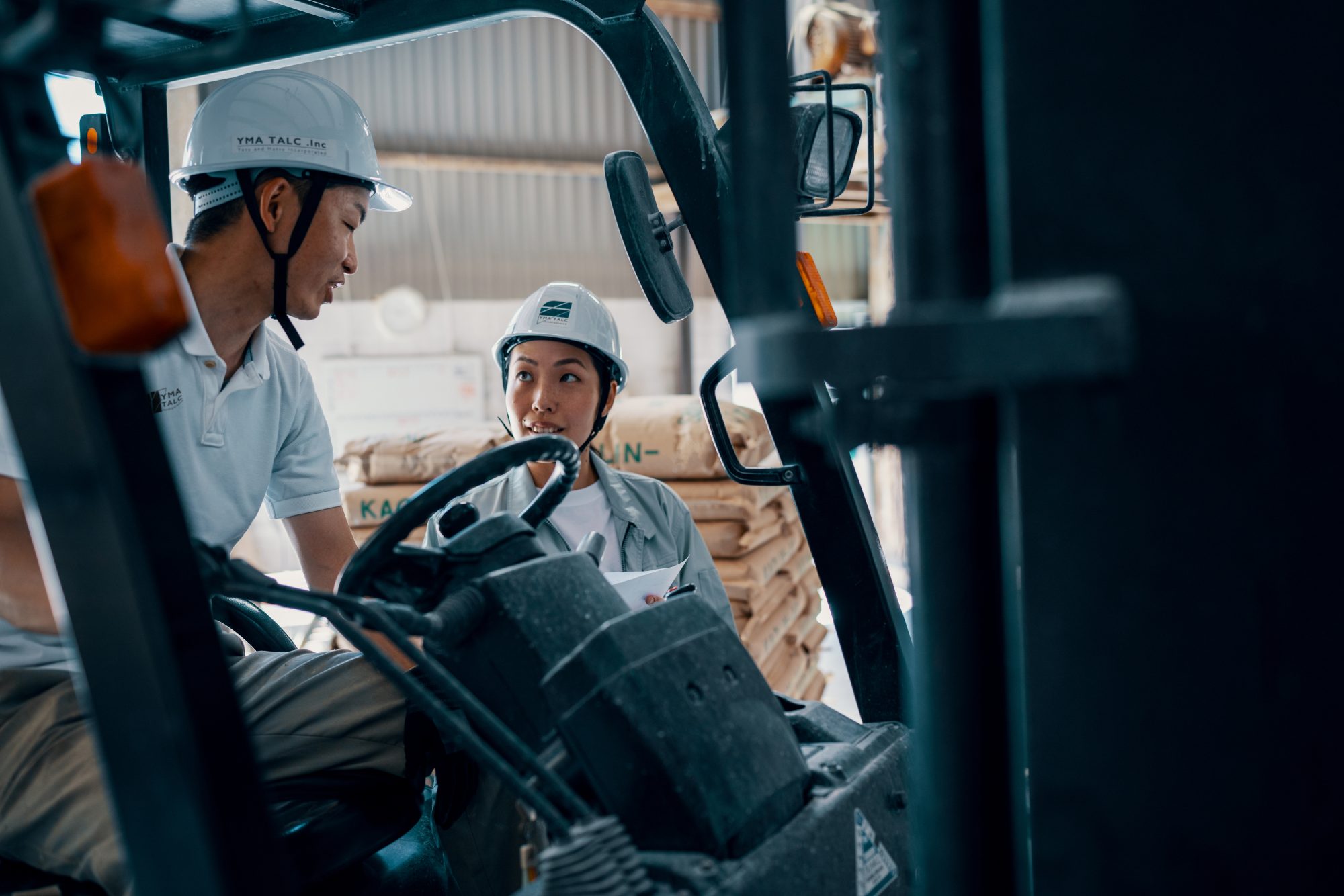 Mid adult female employer speaking with male employee in a shipping warehouse