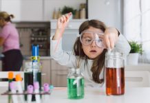 Child playing making some experiments , while her mother working in the kitchen