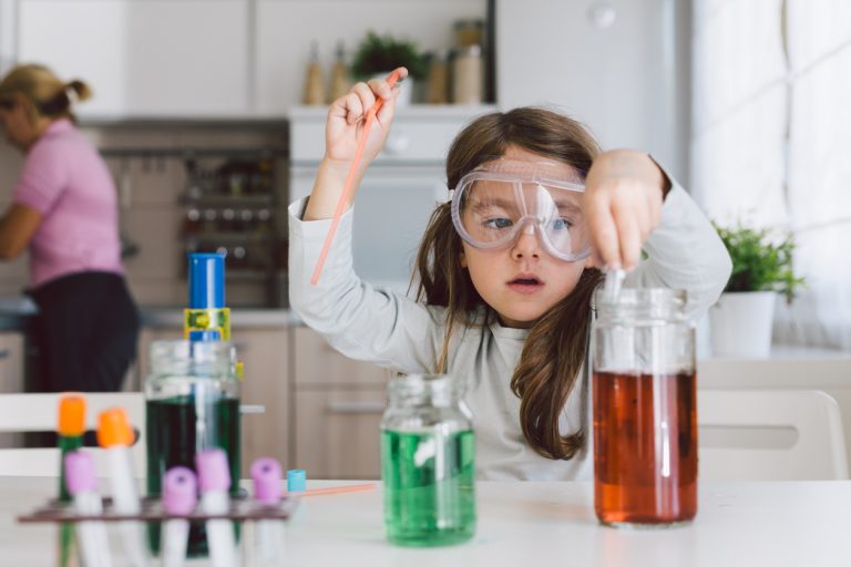 Child playing making some experiments , while her mother working in the kitchen