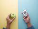 holding diabetic measurement tools, apple on table .