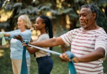 African American mature man practicing with power band on exercise class in nature.