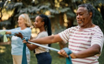 African American mature man practicing with power band on exercise class in nature.