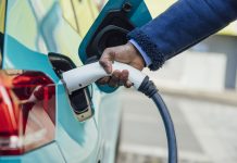 A side view close up shot of an unrecognisable mid adult businessman wearing formal businesswear putting his electric car on charge at a public charging point in Newcastle upon Tyne in the North East of England.