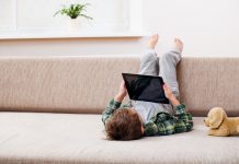 Cute little boy playing with a tablet pc on sofa at home