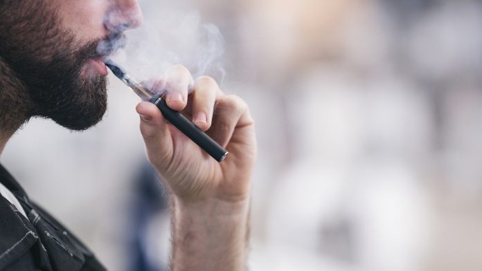 Young male worker smoking electronic cigarette