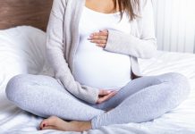 A pregnant woman holding her baby belly at home