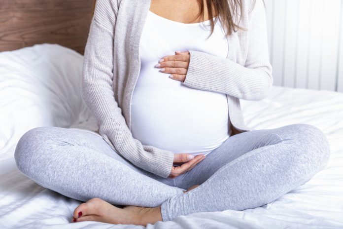 A pregnant woman holding her baby belly at home