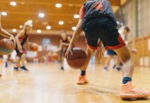 Young Basketball Player on Practice Session. Youth Basketball Team Bouncing Balls on Sports Court. Group of Kids Training Basketball Together