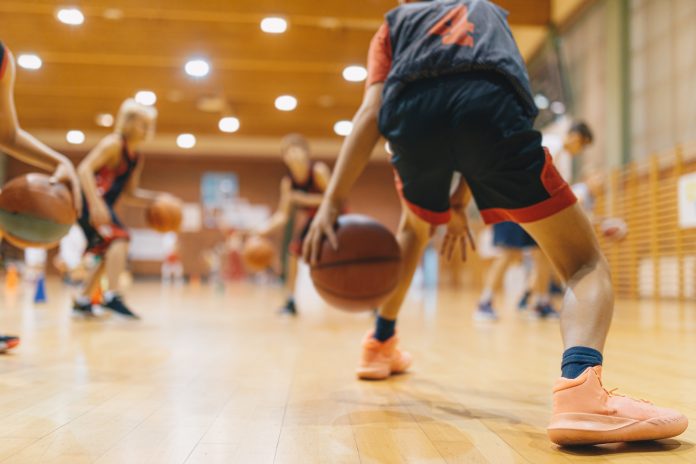 Young Basketball Player on Practice Session. Youth Basketball Team Bouncing Balls on Sports Court. Group of Kids Training Basketball Together