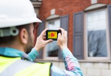 Engineer using thermal camera to analyse the heat loss of a house