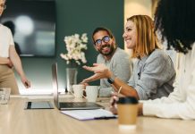 Business woman talking to her colleagues during a meeting in a boardroom. Group of happy business people working together in a creative office, social discourse and intellectual humility