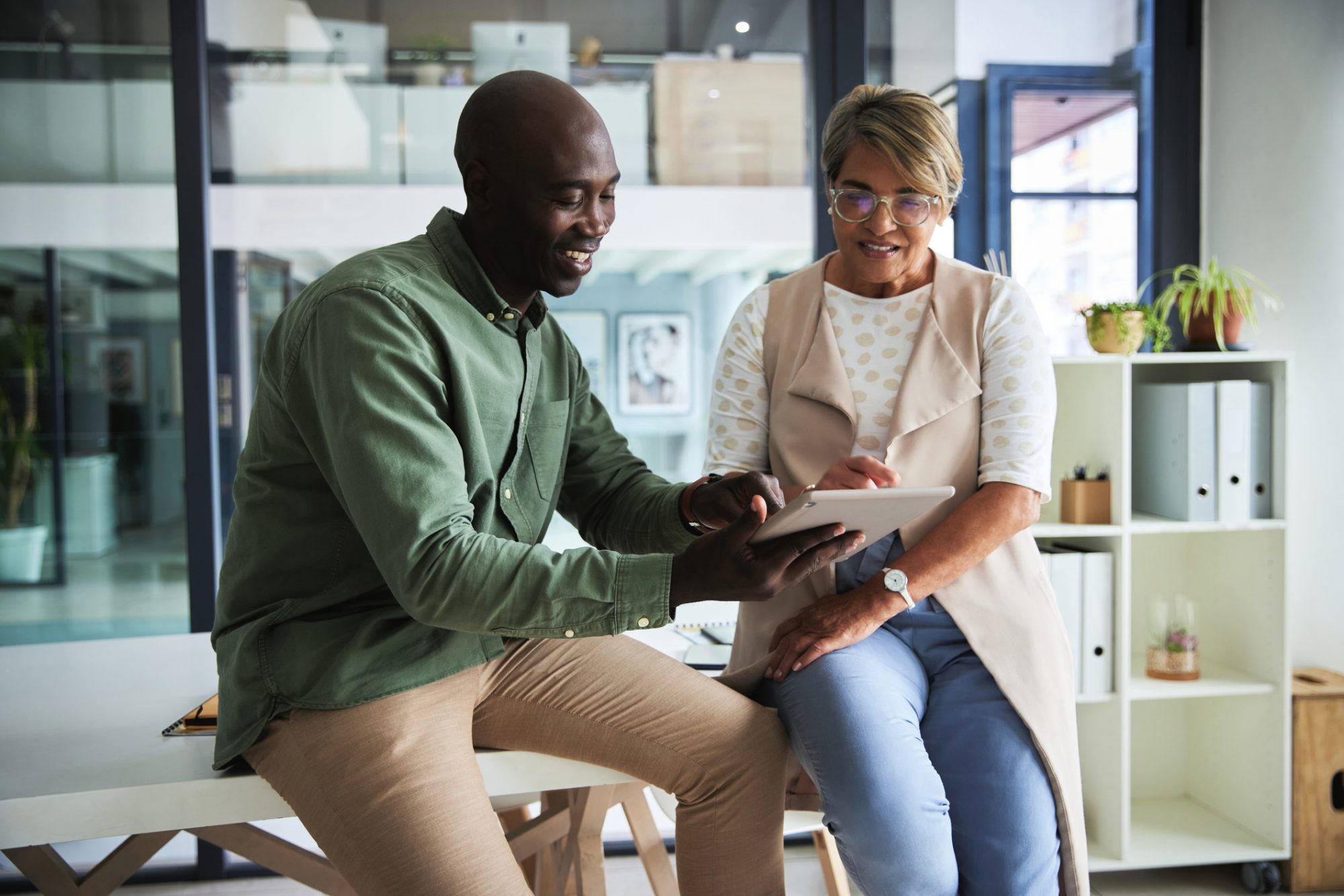 People with tablet for collaboration, planning meeting and web design for website launch. Team communication, app development at digital startup with black man and woman working together in office