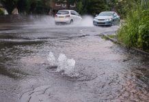 cars driving through flooded road caused by burst water main