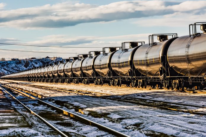 A very long oil train passing through a railyard in Havre, Montana, transporting fossil fuel from the oil fields of Williston, North Dakota. High resolution color photograph with copy space for your message. Horizontal composition.