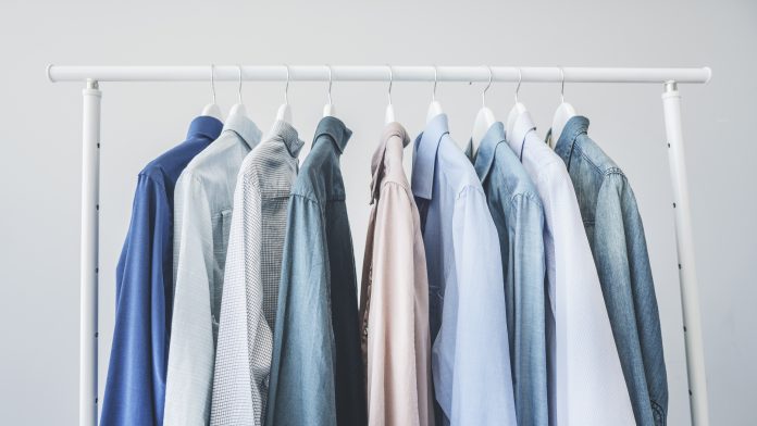 Assorted blue shirts hanging on wooden hangers