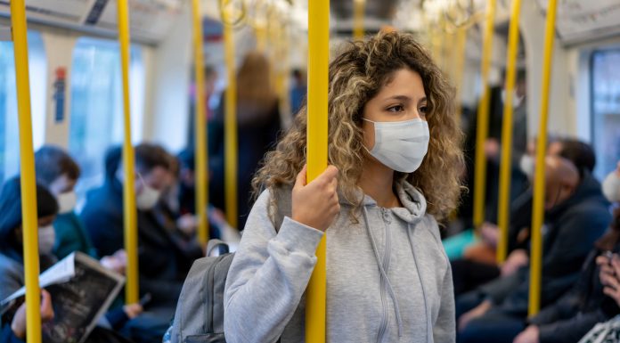 Beautiful young woman riding on the metro wearing a facemask to avoid an infectious disease - COVID-19 lifestyle concepts