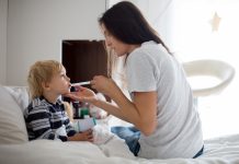 Mother, checking her son for fever with digital thermometer