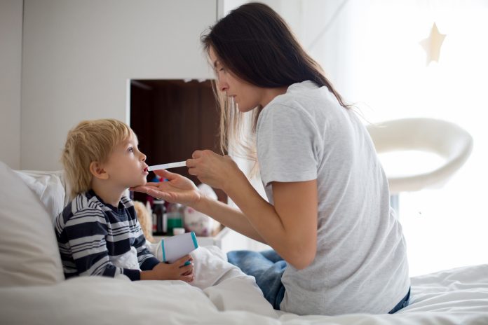 Mother, checking her son for fever with digital thermometer