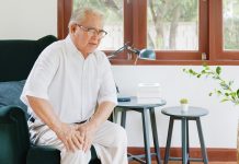Old Asian senior man feel pain, ache, hurt at knee while standing and sitting at home, osteoarthritis concept
