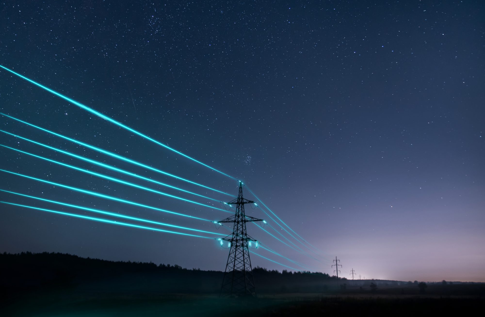 Electricity transmission towers with glowing wires against the starry sky.