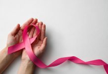 Woman holding pink ribbon on white background, top view with space for text. Breast cancer awareness concept