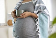 Pregnant woman wrapped in blanket with cup in hands drink hot tea. Natural treatment, remedies, homeopathy to treat illness while pregnancy. Herbal tea for healthy pregnance.