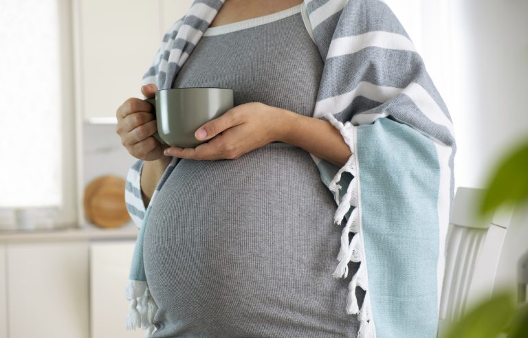 Pregnant woman wrapped in blanket with cup in hands drink hot tea. Natural treatment, remedies, homeopathy to treat illness while pregnancy. Herbal tea for healthy pregnance.